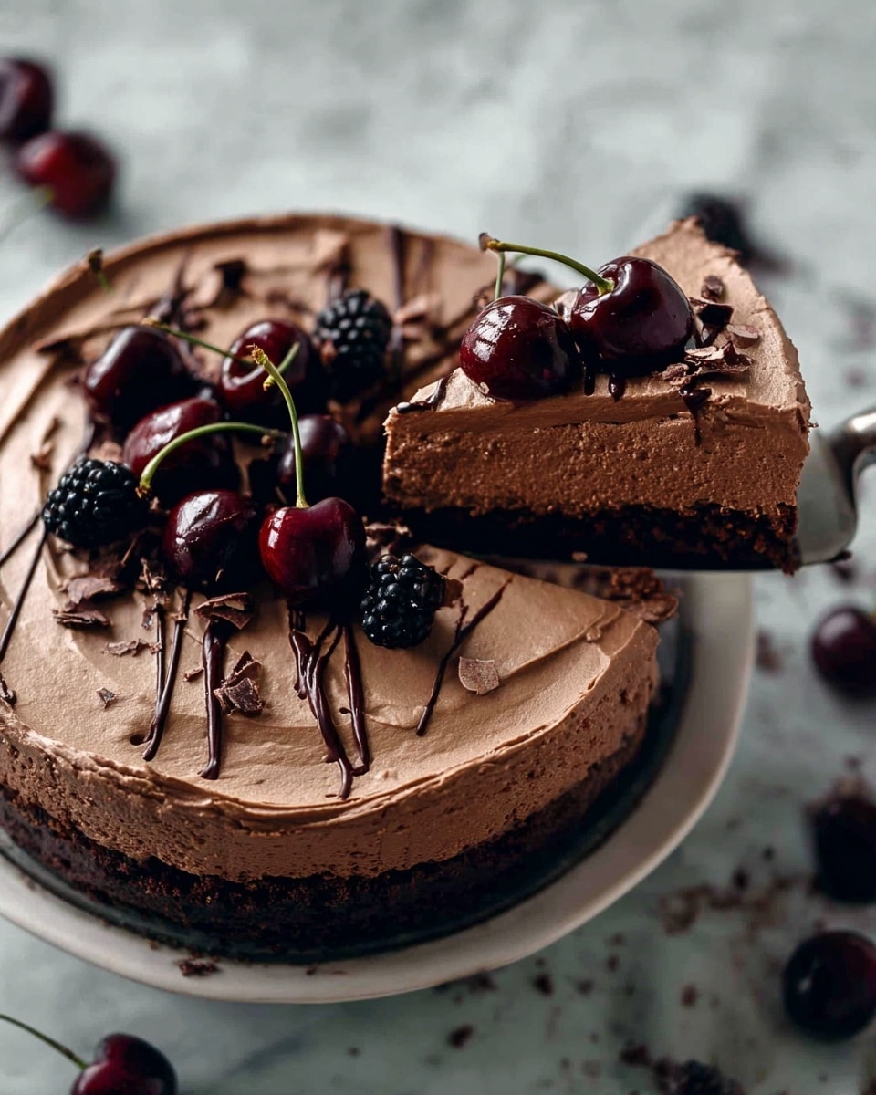 The image shows a rich chocolate cake inside a round metal baking pan, placed on a white marbled surface. The cake has three visible layers: a dark, crumbly base at the bottom, a thick middle layer of smooth, dense chocolate filling in a medium brown shade, and on top, a thick spread of lighter brown chocolate frosting with swirled texture. The top layer is decorated with fresh dark cherries and a few blackberries, adding contrast with their deep red and black tones. A slice is cut out and slightly moved forward from the cake, showing the clean layers. The background is dark and blurred, making the cake the main focus. Photo taken with an iphone --ar 4:5 --v 7