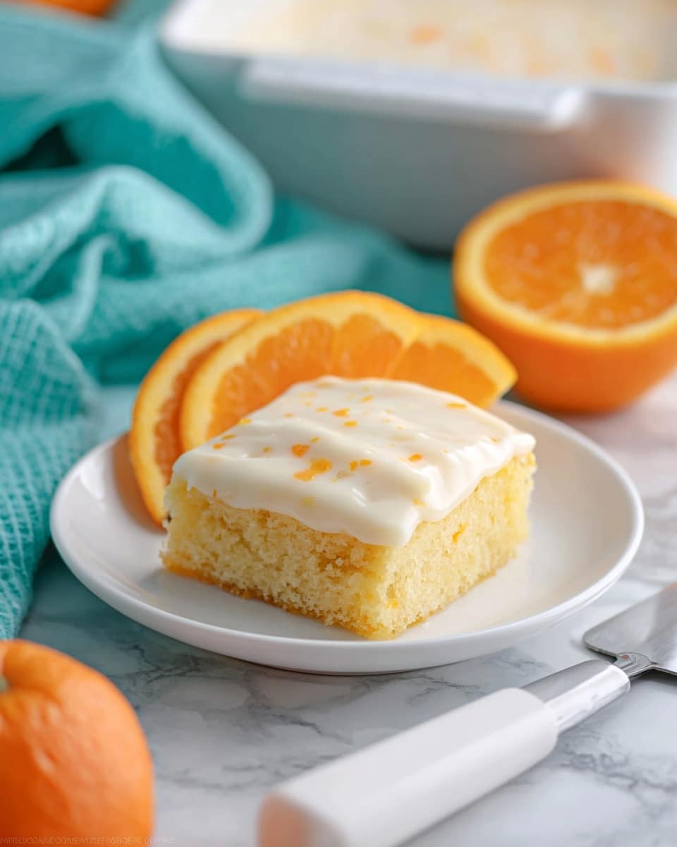A square piece of moist yellow cake sits on a white plate, topped with a smooth creamy white frosting that has small orange specks scattered throughout. Behind the cake, there are three thin orange slices arranged in a slight arc, adding a fresh pop of bright orange color. The plate is set on a white marbled surface, with a folded turquoise cloth in the background and part of a white baking dish visible behind it. In the foreground, a half orange and a white handle with a metal cake server are also visible, hinting at a fresh, citrus theme. photo taken with an iphone --ar 4:5 --v 7