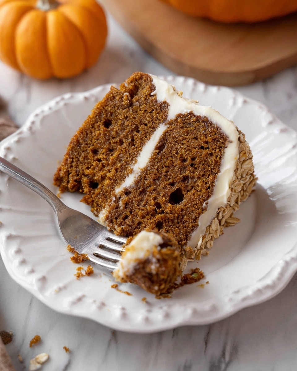 A single slice of brown cake with a moist texture and small holes throughout, showing some oats near the top edge, sits on a white scalloped plate. The cake has one visible layer with a thin spread of white frosting along the side edges. In front of the slice, a silver fork holds a small piece of the cake, with crumbs scattered on the plate around it. Behind the plate is a small orange pumpkin and a white marbled surface beneath. Photo taken with an iphone --ar 4:5 --v 7