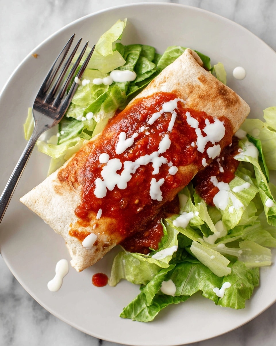 A folded burrito with a soft light brown tortilla sits in the middle of a white plate, surrounded by fresh green lettuce leaves that add texture and color around it. The burrito is topped with a thick red salsa sauce that looks chunky and slightly glossy, and white sauce drizzled unevenly over the salsa and burrito. A fork rests on the edge of the plate, with some white sauce drops scattered around the plate on a white marbled surface. photo taken with an iphone --ar 4:5 --v 7