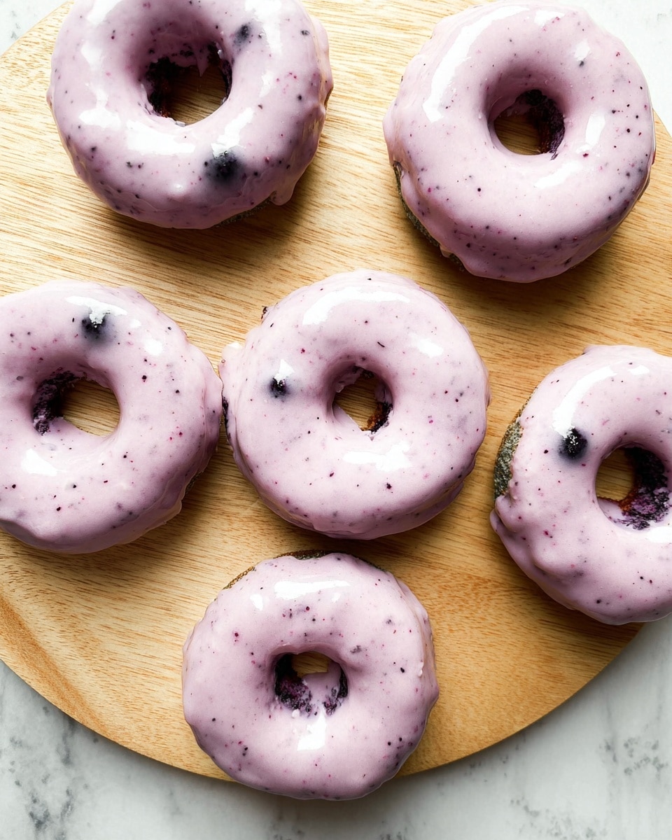 The image shows a step-by-step process of making blueberry donuts. In the first part, a clear glass bowl holds a mix of dry flour and wet batter topped with a pile of dark purple blueberries being mixed with a light blue spatula. In the second part, a metal donut pan holds six portions of lilac-colored batter with visible blueberries being filled into each mold by a woman's hand squeezing a piping bag. The third part shows a beige bowl with smooth, thick lavender glaze being stirred by a spoon held by a woman's hand. The last part presents five donuts on a black wire rack over white parchment paper, with the top half of each donut coated in shiny purple glaze, and a woman's hand using a spoon to spread the glaze on one donut, all on a white marbled surface. Photo taken with an iphone --ar 4:5 --v 7