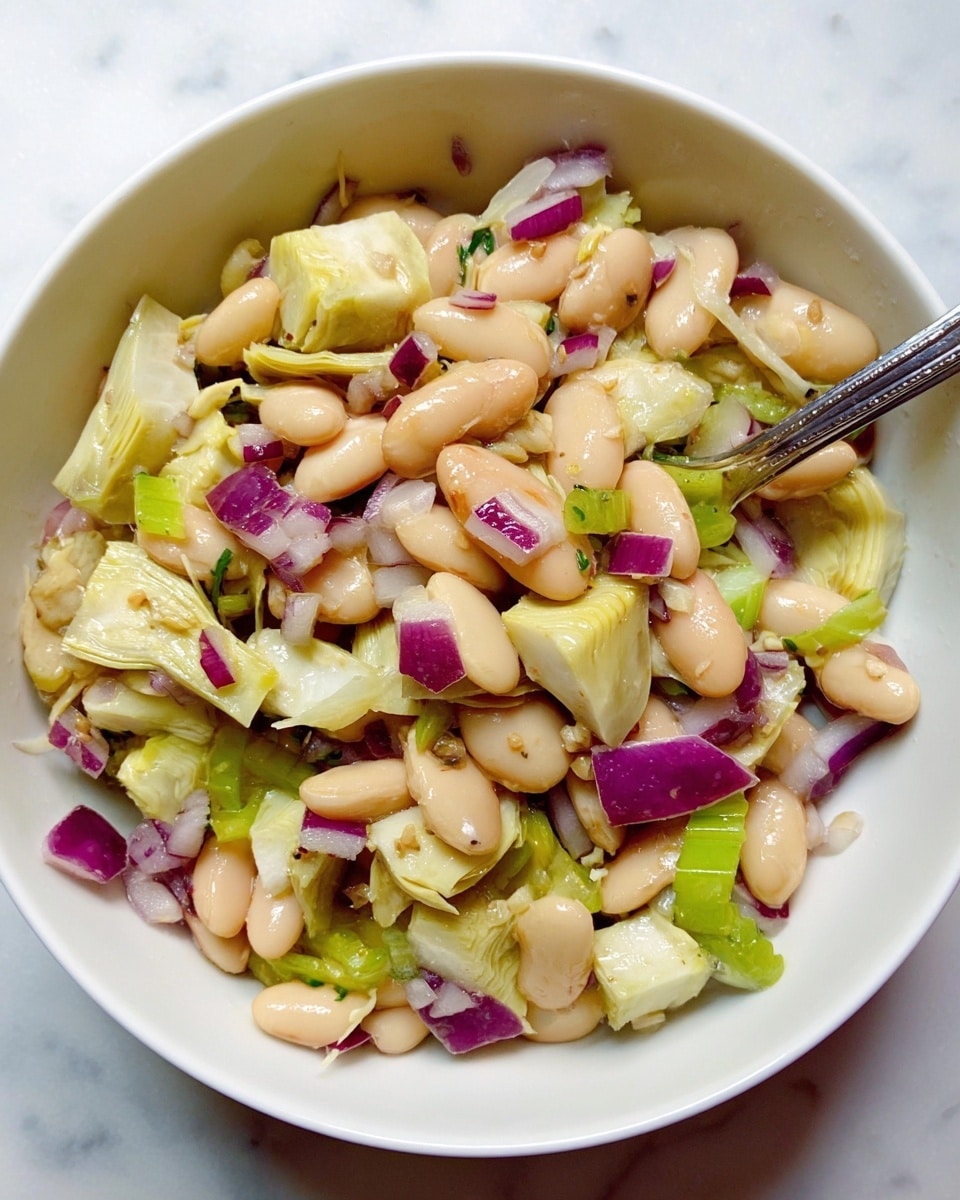 A white bowl filled with a salad made of three main layers: the bottom layer contains light beige beans that are oval and smooth; the middle layer has pale yellow artichoke hearts cut into chunks with a soft, slightly fibrous texture; scattered throughout are slices of finely chopped purple-red onion, adding a pop of color and crunch; there are also thin slices of light green celery mixed in, adding freshness. The salad appears lightly dressed with a glossy coating, and a silver fork rests inside the bowl. The bowl is placed on a white marbled surface. Photo taken with an iphone --ar 4:5 --v 7