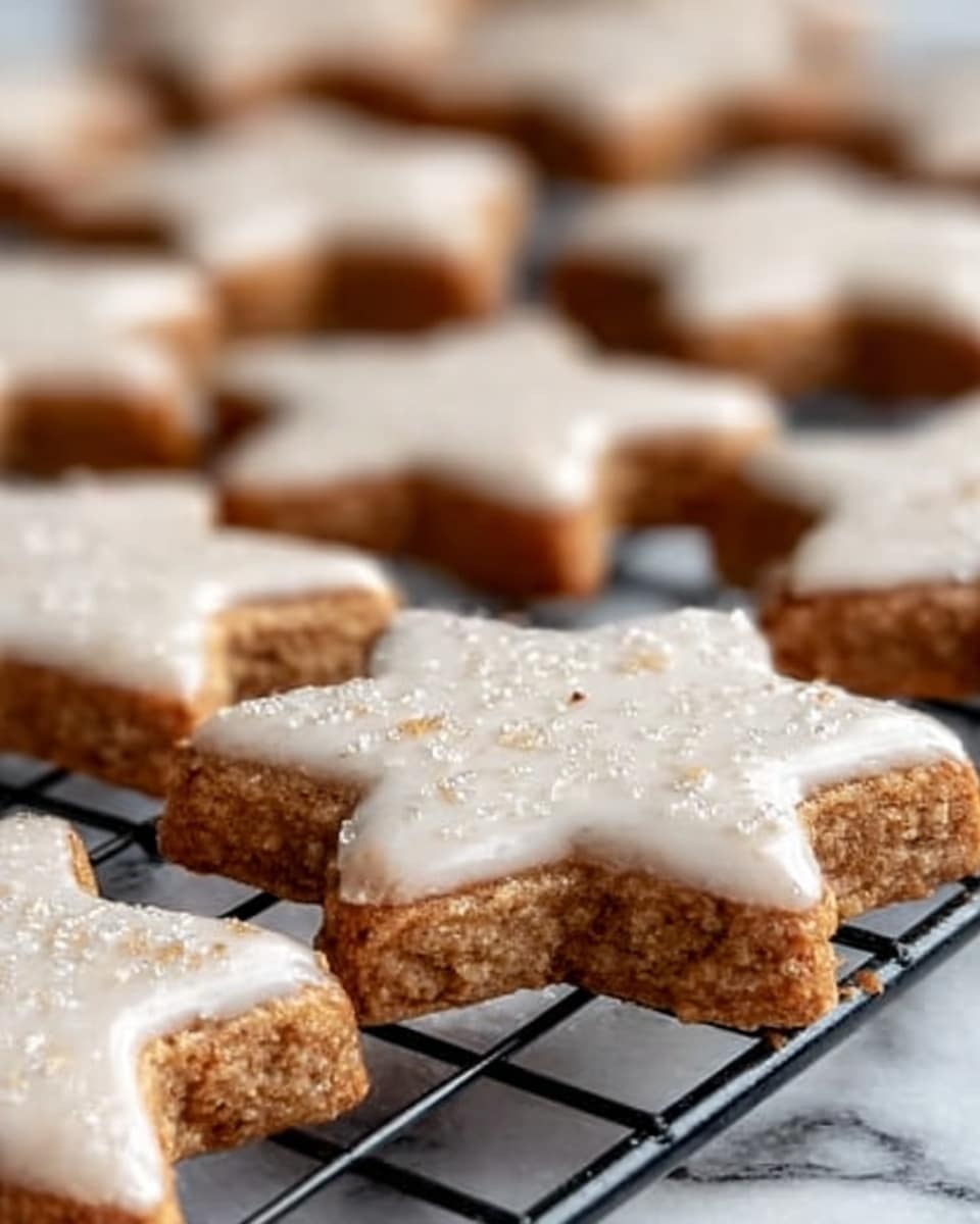 The image shows close-up of star-shaped cookies on a black wire rack. The cookies have two layers: the bottom layer is light brown with a rough texture, and the top layer is a white glaze with a shiny, smooth surface, sprinkled lightly with sugar. The cookies are arranged on the rack against a white marbled surface. The focus is on two cookies in front, with many more slightly blurred in the background. photo taken with an iphone --ar 4:5 --v 7