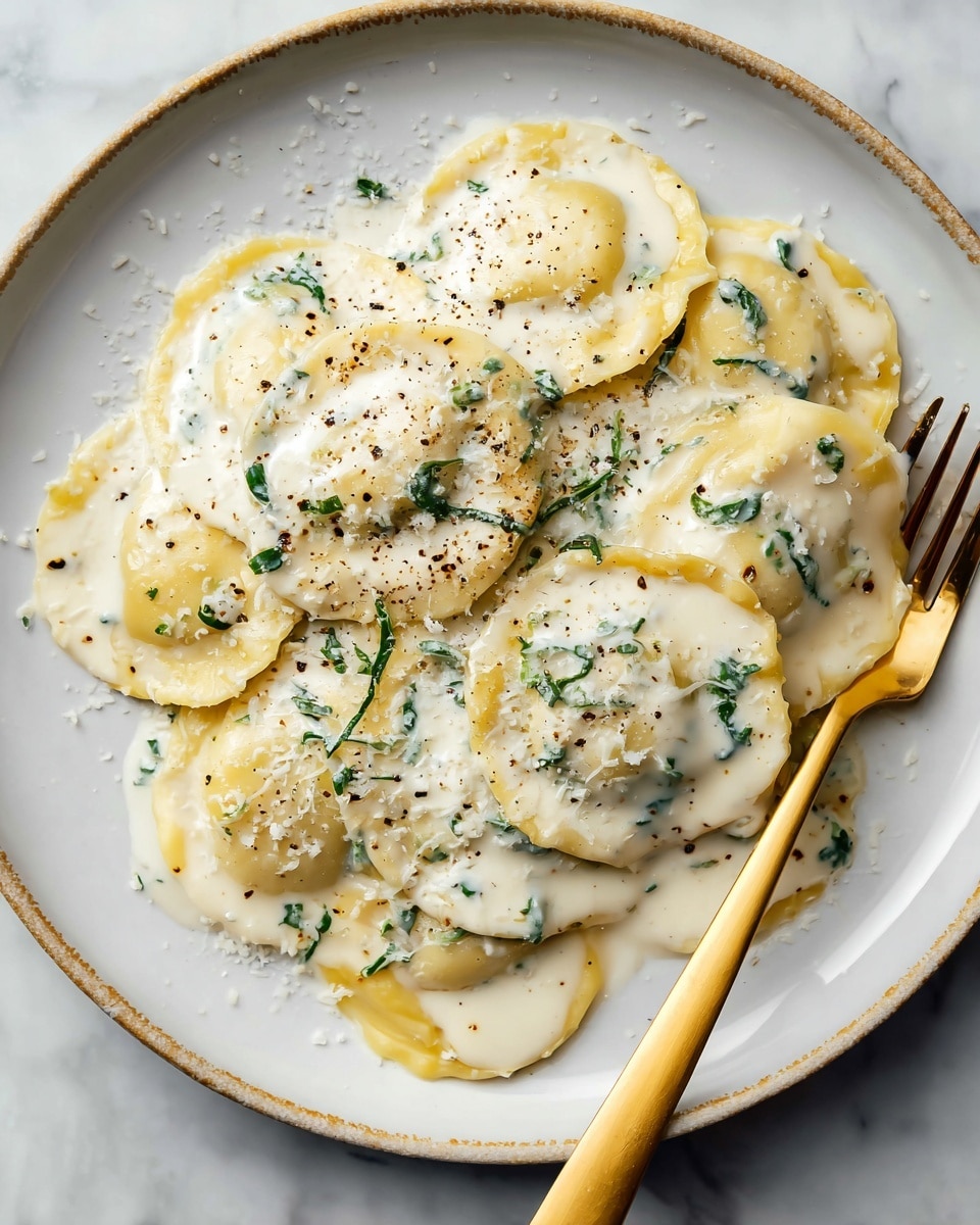 A beige plate holds a single layer of round ravioli with crimped edges, each pale yellow with a soft texture. The ravioli are covered in a creamy white sauce speckled with small bits of green herbs. On top, there is a sprinkling of finely grated white cheese and a light dusting of ground black pepper. A silver fork rests on the right side of the plate, slightly touching the pasta. The plate sits on a white marbled surface. Photo taken with an iphone --ar 4:5 --v 7