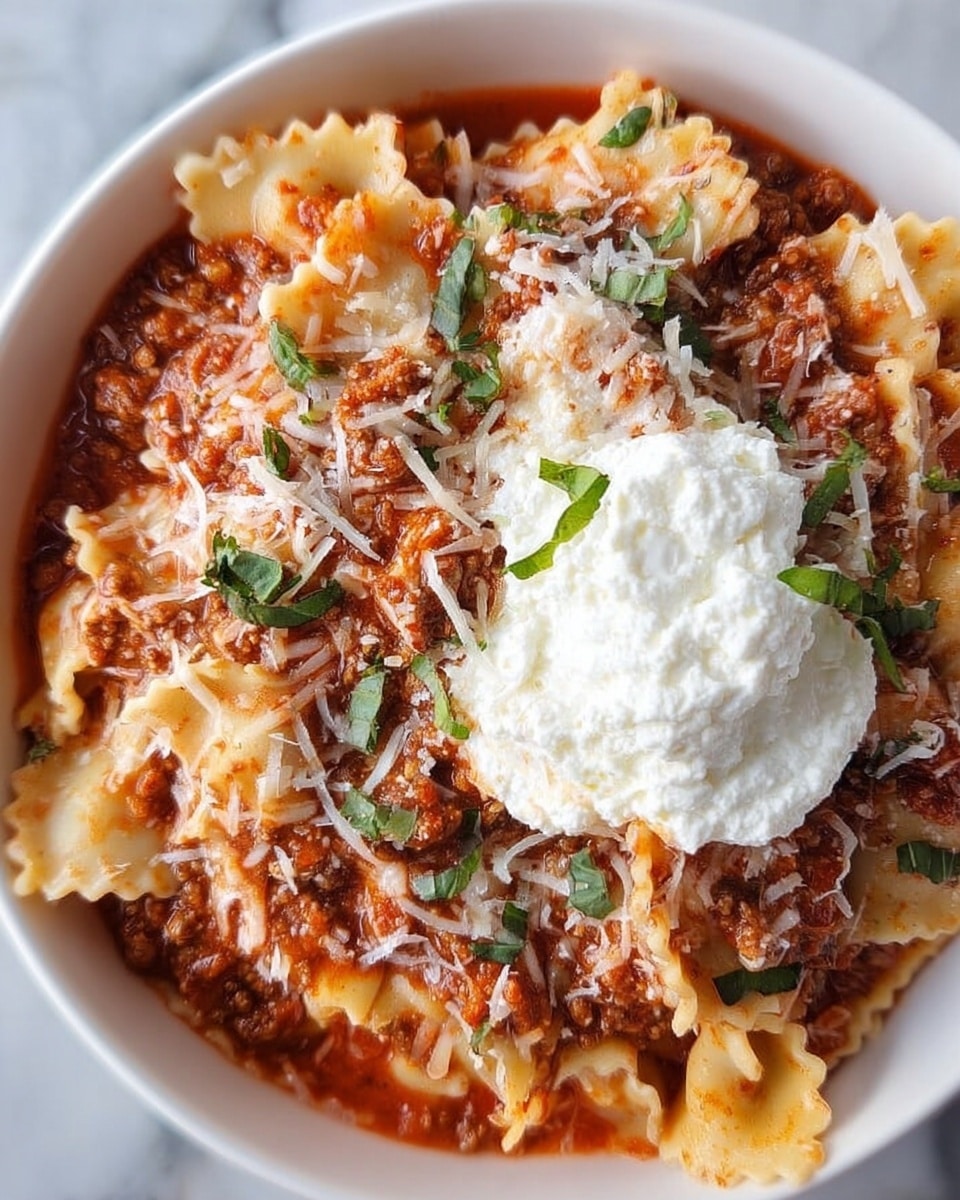 A close-up image of a bowl filled with layers of pasta sheets with wavy edges mixed in a thick red tomato meat sauce, topped with finely shredded white cheese and small green basil leaves scattered on top; a dollop of smooth white ricotta cheese sits on one side of the bowl, which is white, all set on a white marbled surface. Photo taken with an iphone --ar 4:5 --v 7