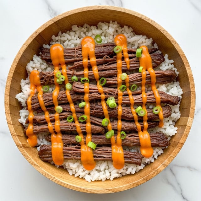 A wooden bowl filled with a base layer of white rice, topped with shredded dark brown meat arranged evenly across the center. Bright orange sauce is drizzled in thick lines over the meat, creating a striking contrast. Small green onion slices are scattered on top of the sauce and meat, adding a fresh pop of color. The bowl is set against a white marbled surface. Photo taken with an iphone --ar 4:5 --v 7