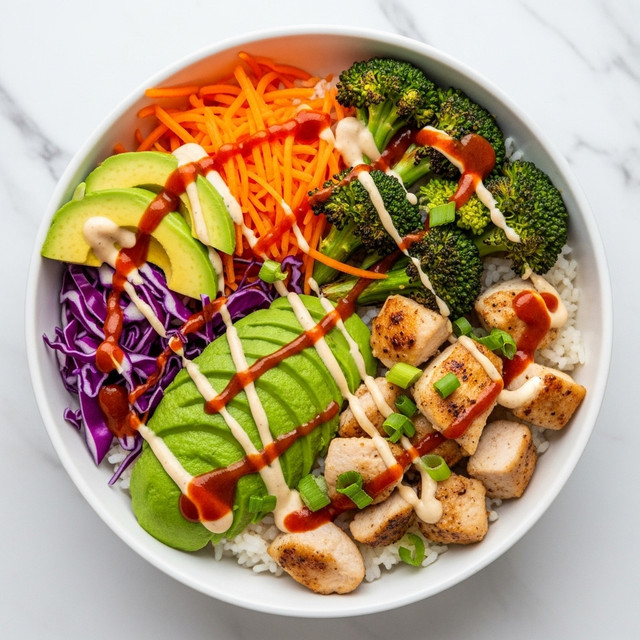 A white bowl sits on a white marbled surface, filled with a colorful rice bowl. At the base is a layer of white rice. On top, there is a mix of roasted broccoli and cooked chicken pieces, both lightly browned and garnished with chopped green onions. Bright orange shredded carrots and purple cabbage sit on one side, while slices of green avocado are neatly arranged beside them. The dish is finished with drizzles of a creamy light sauce and a reddish hot sauce over the chicken and vegetables. photo taken with an iphone --ar 4:5 --v 7