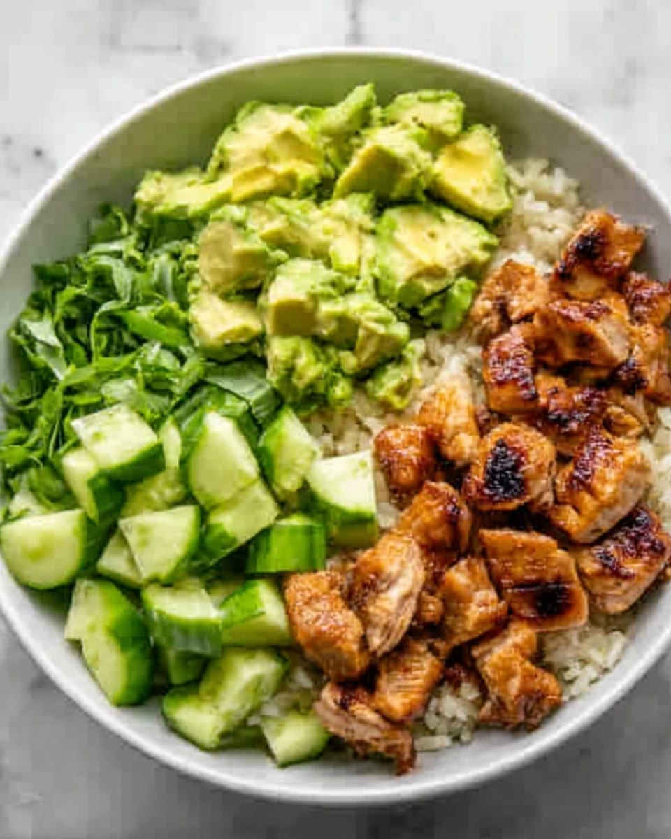 A white bowl with four sections of food seen from above, placed on a white marbled surface. The first section has chopped green cucumbers with a fresh, shiny texture. Next to it is grilled chicken, cooked to a golden brown with visible grill marks, showing a slightly crispy texture. Another section has diced avocado, light green with a soft, smooth texture. The last section contains rice mixed with herbs, pale in color with small green bits. photo taken with an iphone --ar 4:5 --v 7