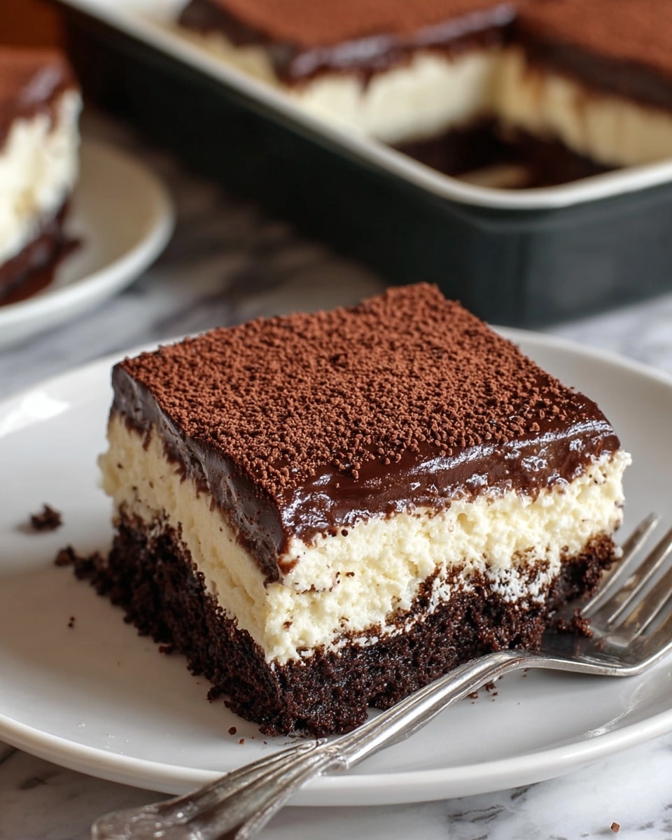 The dessert is a square-shaped layered cake on a white plate, showing three clear layers. The bottom layer is thick, dark brown, and dense like moist chocolate cake. The middle layer is creamy white, smooth, and soft, resembling a cheesecake or cream cheese filling. The top layer is a shiny, rich dark brown chocolate ganache, dusted evenly with a fine layer of cocoa powder that adds a textured matte finish. A silver fork lies next to the cake on the plate, and in the background, there is a black baking tray with more cake pieces slightly out of focus. The surface beneath everything shows a white marbled texture. photo taken with an iphone --ar 4:5 --v 7
