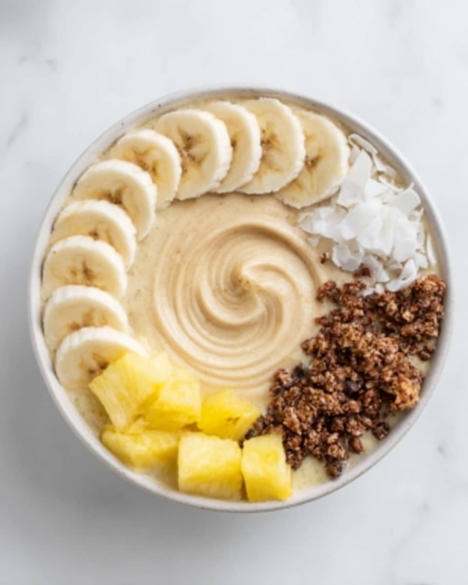 A white bowl on a white marbled surface contains a smoothie bowl with five distinct layers arranged in sections. Starting from the top left, there is a layer of sliced bananas with light yellow tones and soft texture. Next to it, moving clockwise, a swirl of creamy beige smoothie fills the center of the bowl. Along the right side, there are white coconut flakes with a rough texture. Below that, a cluster of dark brown crunchy granola pieces contrasts with the smooth layers. Finally, in the bottom left section, small chunks of bright yellow pineapple add a fresh and juicy look. Photo taken with an iphone --ar 4:5 --v 7