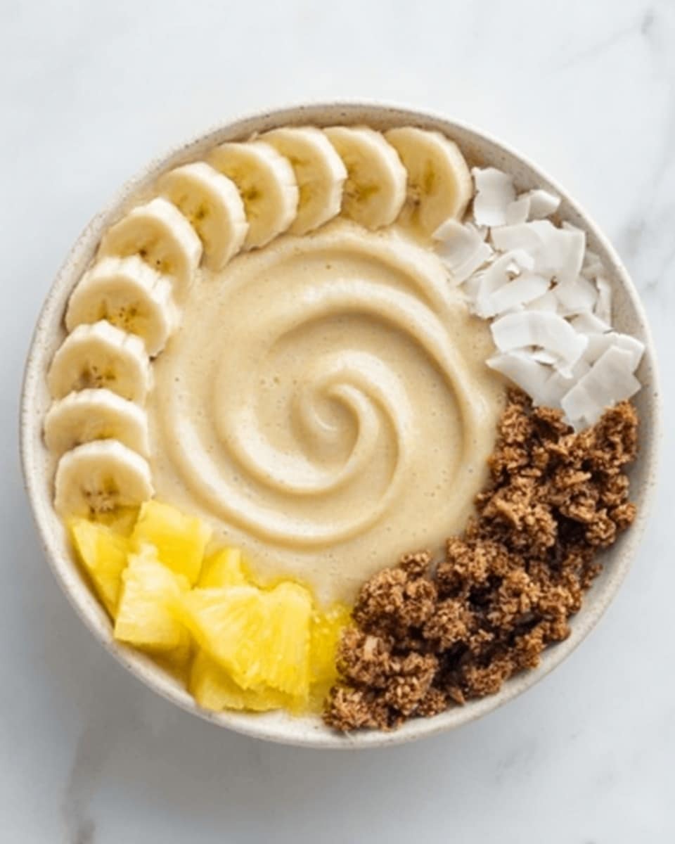 A white bowl filled with a smoothie base topped with four distinct sections arranged in a circle: light yellow pineapple chunks in one section, thinly sliced banana pieces forming a slightly overlapping spiral in the next, white coconut flakes in another section, and dark brown granola with clusters in the last section. The smoothie base is smooth and creamy with a beige color, and there is a subtle spiral swirl at the center. The bowl rests on a white marbled surface, and to the right, a wooden spoon is partly visible. Photo taken with an iphone --ar 4:5 --v 7